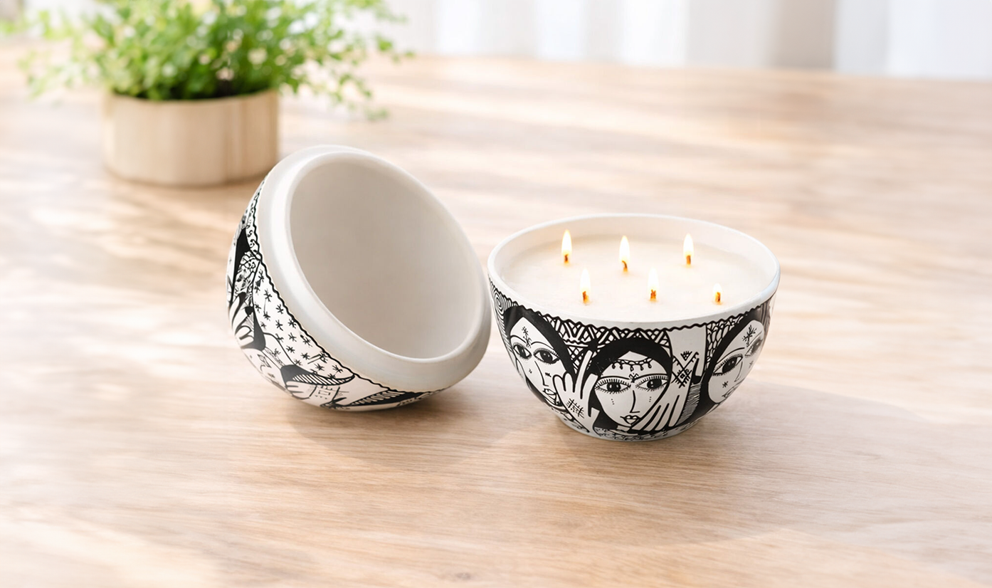 Lit candle on a wooden side table next to books and eyeglasses, with a sofa in the background.
